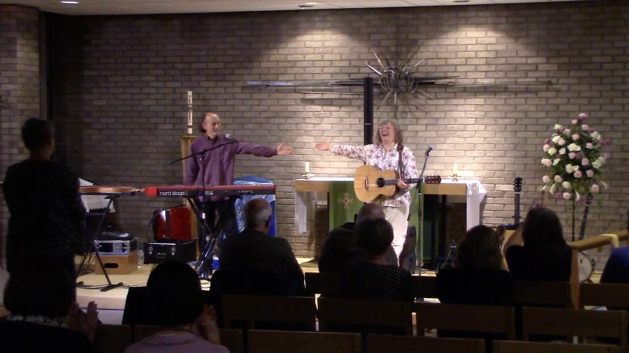 Sarah and Duncan taking applause at the end of a show. Audience in foreground. Brick wall well lit in background.